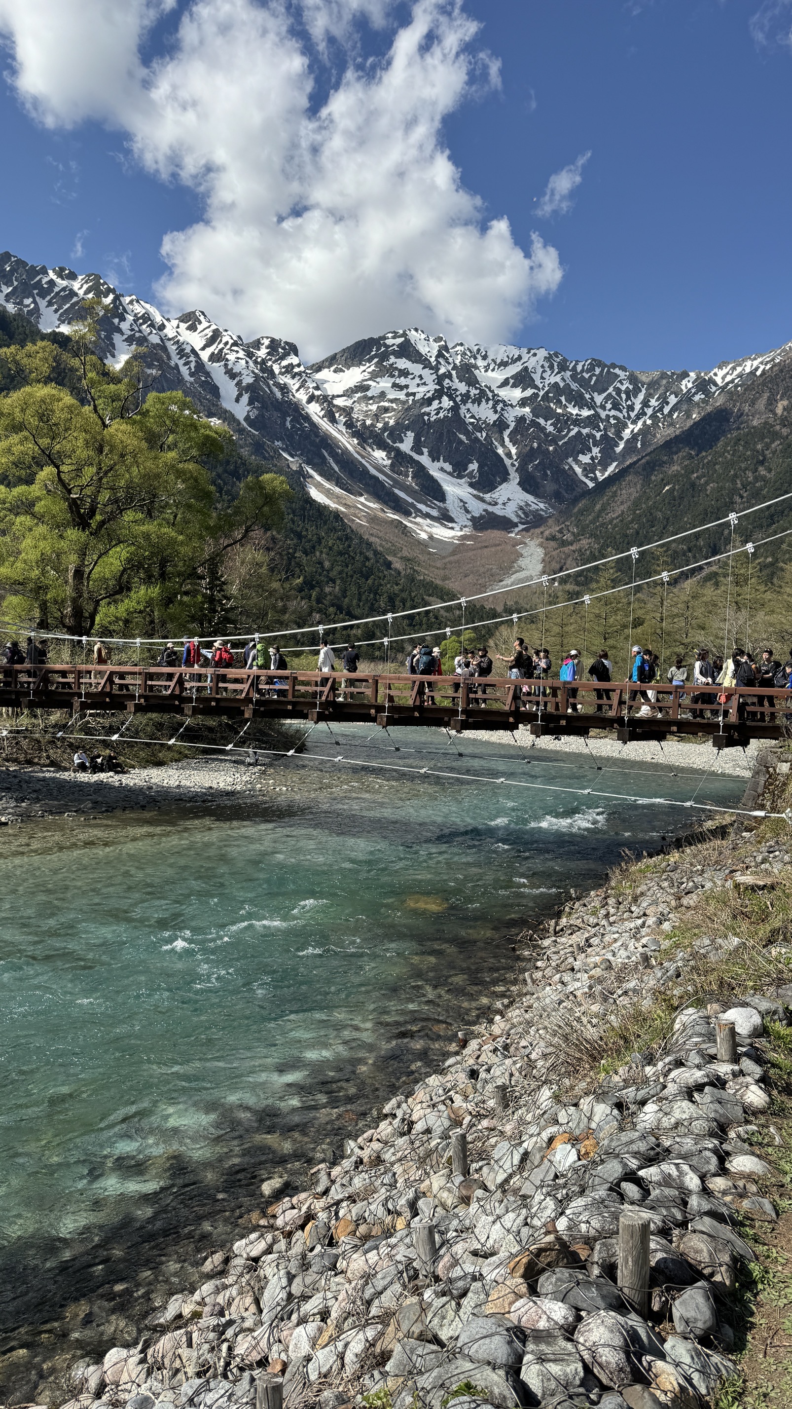 Wooden footbridge crossing mountain stream with steep forest cliffs, Kamikochi