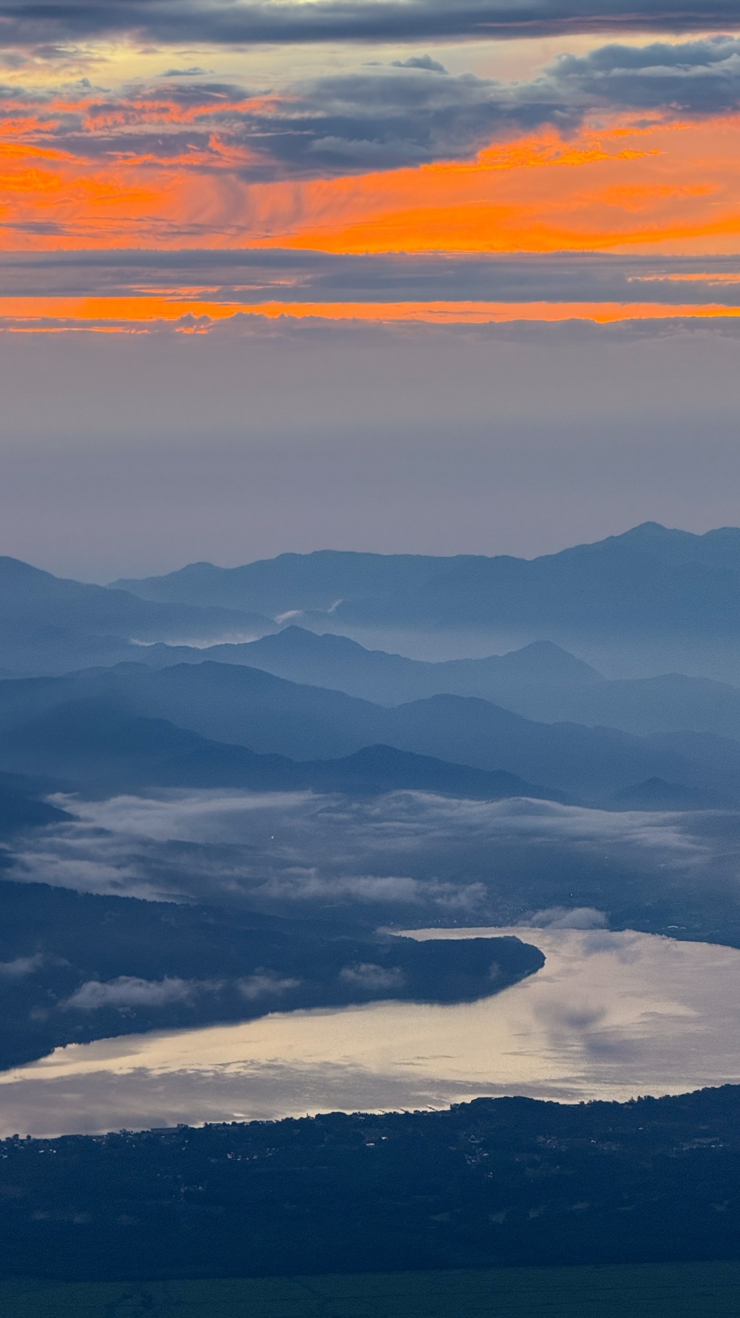 Fiery orange sunrise breaking over layered mountain ridges from Mount Fuji