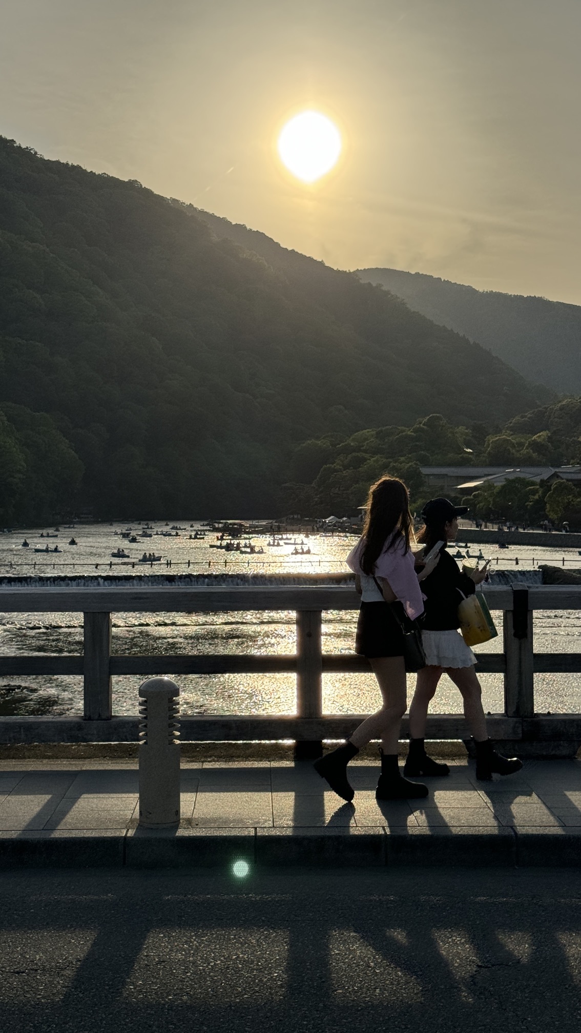 Peaceful riverside moment at ancient bridge with silhouettes at sunset, Arashiyama