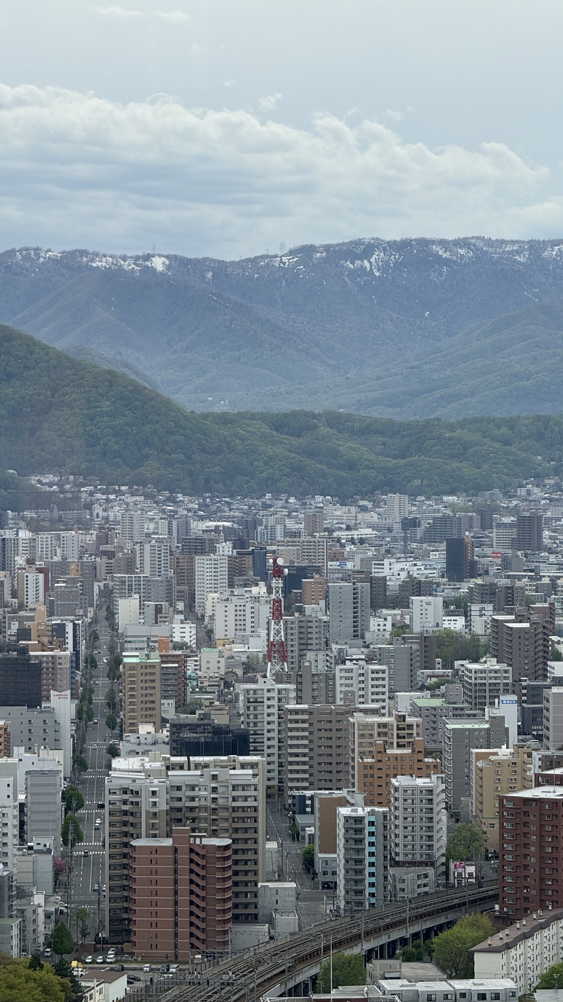 Sapporo cityscape with buildings and forested hills in background, Hokkaido